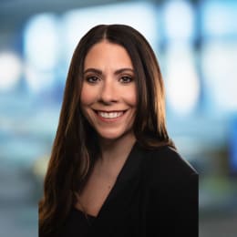 a woman wearing a suit and smiling at the camera