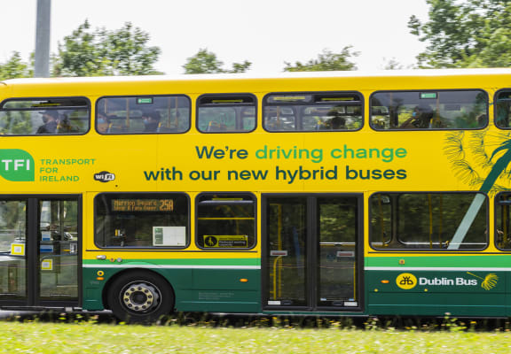 a double decker bus with a sign that says we're driving change with our new hybrid
