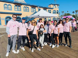 a group of people wearing pink shirts standing on a boardwalk