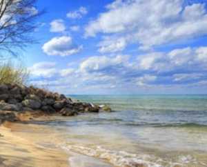 A beach with rocks and water under a cloudy sky.