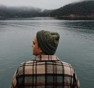 A person wearing a hat and a red scarf is looking down.