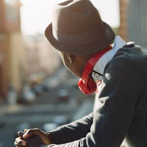 A person wearing a hat and a red scarf is looking down.