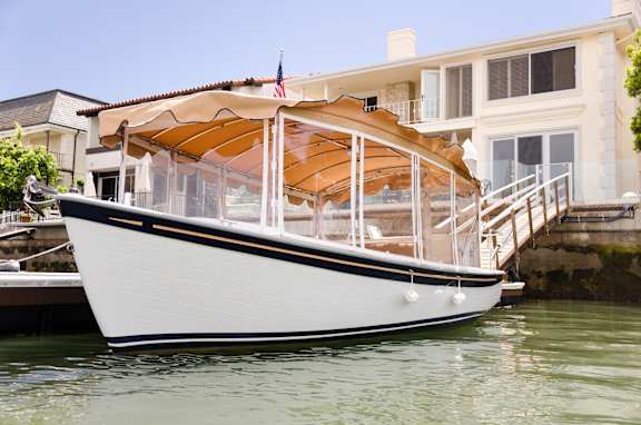 A white boat with a brown canopy is docked in the water.