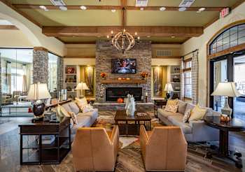 A living room with a stone fireplace and a chandelier.