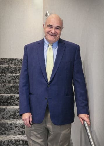 an older man wearing a blue suit and a yellow tie