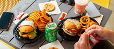 A meal consisting of burgers, fries and onion rings is served on a black tray.