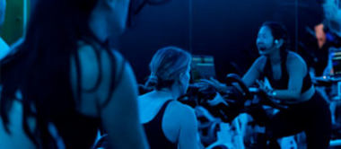 A group of people are working out on exercise bikes in a dimly lit room.