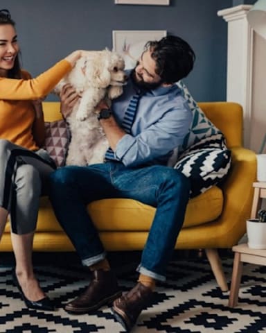 a man and woman sitting on a couch with a dog at The Trilogy Apartments, Manchester, M15 4RU