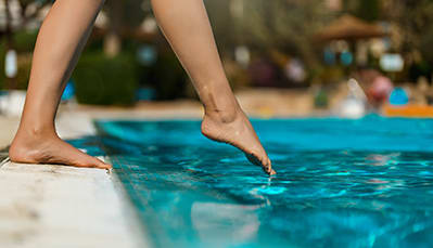 person dipping foot in the pool