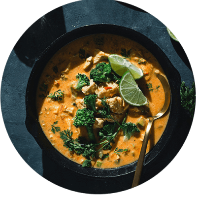 a bowl of chicken and broccoli curry with a spoon
