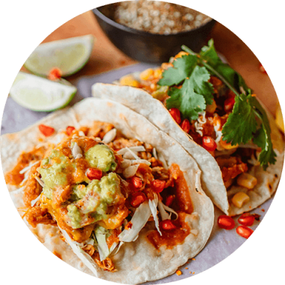two tacos on a plate with a bowl of rice and a lime