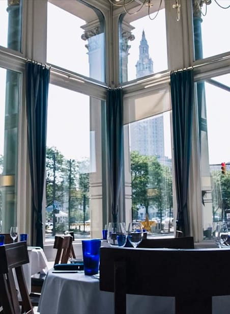 A restaurant with a view of a city skyline through large windows.