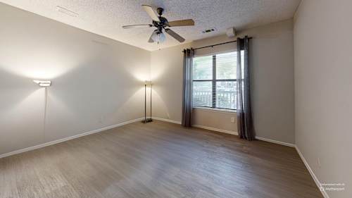 A kitchen with a white counter and a black trash can.