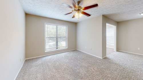 A kitchen with a white counter and a black trash can.