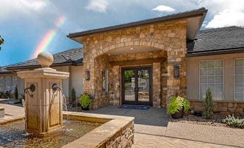 A house with a stone facade and a fountain in front.