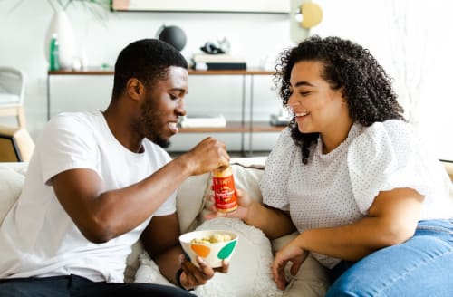 a man and a woman sitting on a couch eating food