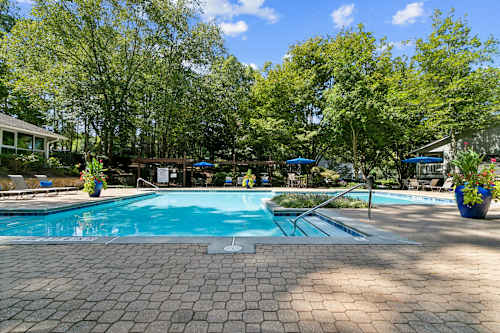 A swimming pool surrounded by lounge chairs and apartment buildings.