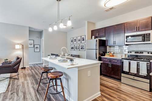 A kitchen with a white island and dark wood floors.
