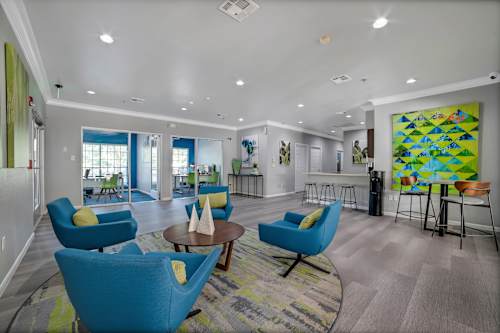 A living room with blue chairs and a painting on the wall.