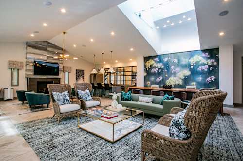 A living room with a large mural on the wall and a variety of seating options.