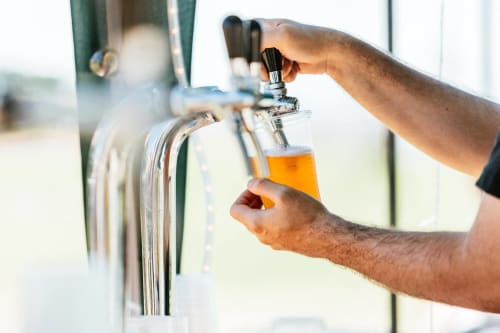 a man holding a bottle of beer in a tap