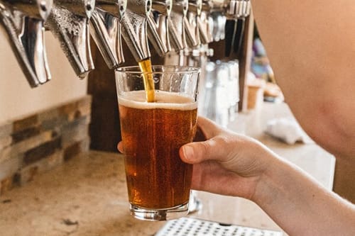 a person holding a glass of beer at a bar