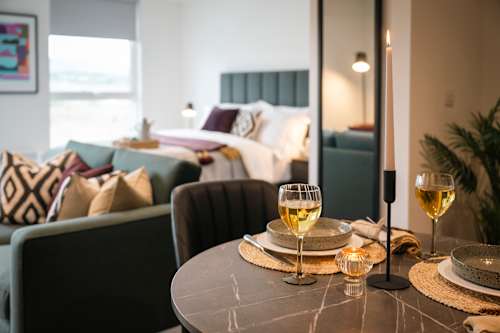 A dining table with two glasses of white wine and a plate.