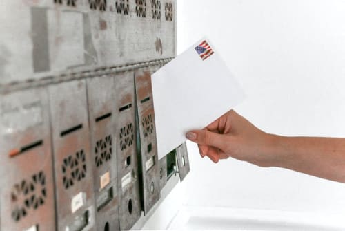 a hand holding a ballot paper in front of a row of lockers