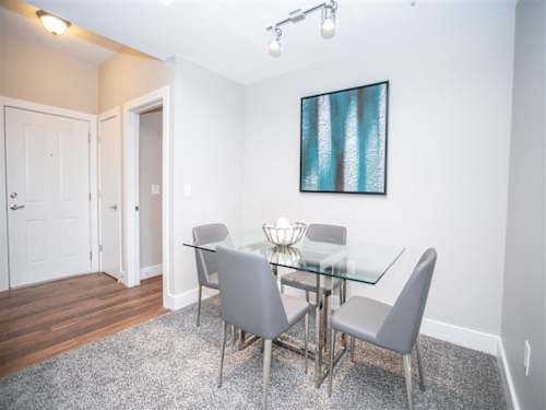 A dining room with a glass table and grey chairs.