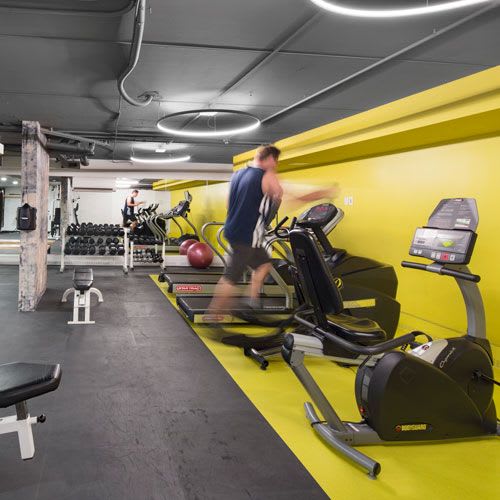 fitness room with exercise equipment and a person running on a treadmill