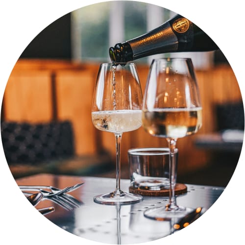 a bottle of wine being poured into two glasses on a table