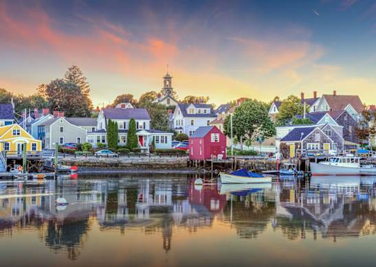A serene harbor scene with boats docked and buildings along the water's edge.
