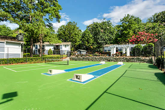 A tennis court surrounded by trees and buildings.