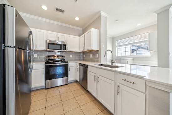 A kitchen with white cabinets and stainless steel appliances.