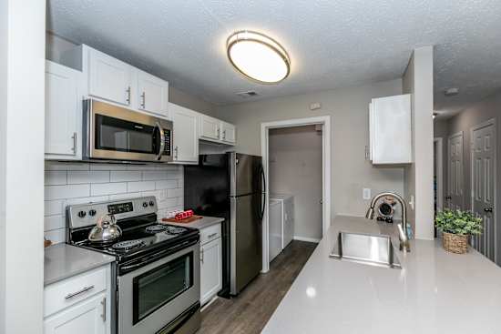 A kitchen with white cabinets and a black refrigerator.
