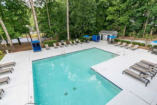 A large swimming pool surrounded by trees and lounge chairs.