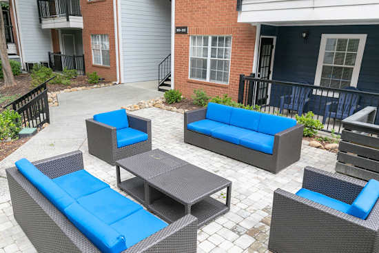 A patio with blue cushions and grey furniture.