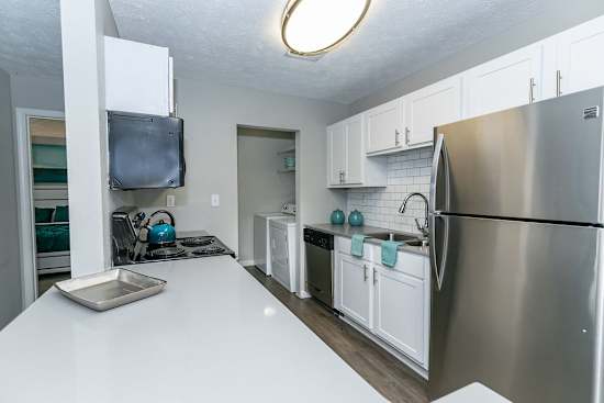 A kitchen with a stainless steel refrigerator and white countertops.
