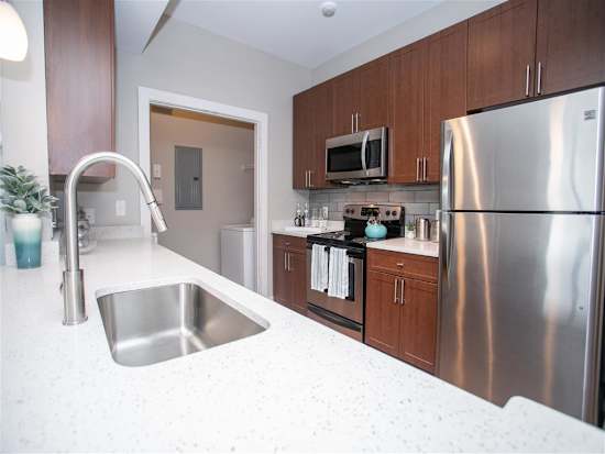 A kitchen with a stainless steel refrigerator, microwave, and sink.