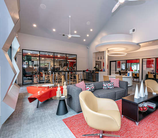 A modern living room with a grey sofa, a red table and a yellow chair.