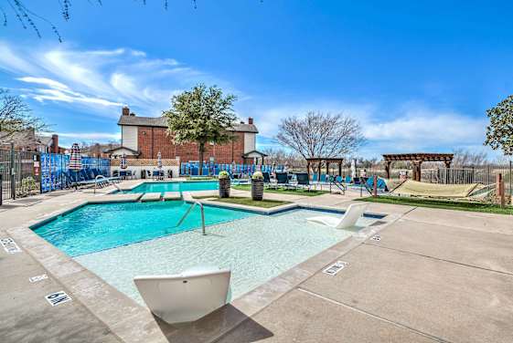 A large outdoor swimming pool with a slide and a white lounge chair at 2803 Riverside, Grand Prairie, Texas
