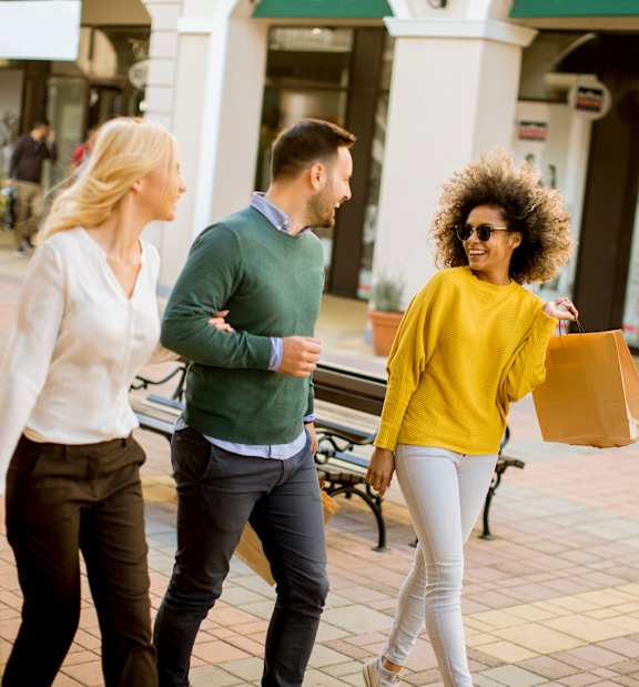 Three people walking in a shopping area.