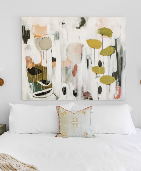 White bed next to picture art showing greenery