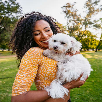 A woman holding a dog in a park