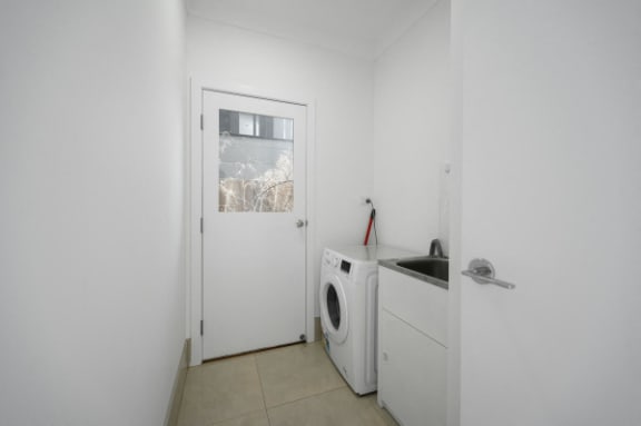 a white laundry room with a washing machine and a door