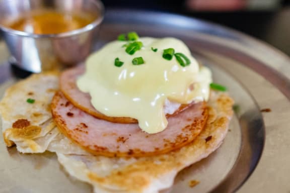 a plate of eggs Benedict with ham
