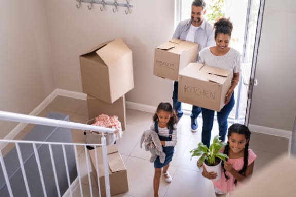 a family carrying boxes down a staircase with their children