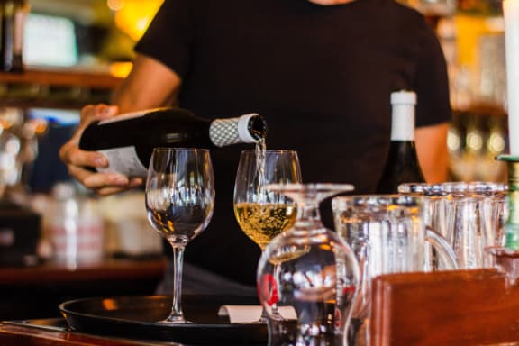 a waiter pouring wine into glasses at a brunch restaurant