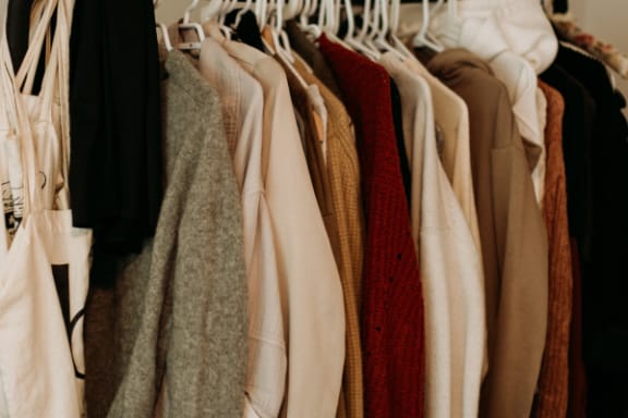 a row of clothes hanging on a rack in a closet