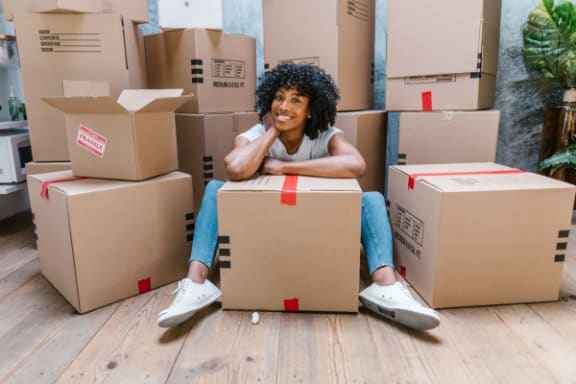 a woman sitting in a pile of cardboard moving boxes